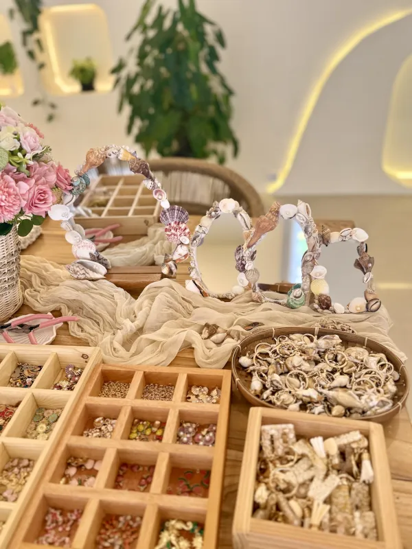 Handmade shell mirrors displayed beside trays of charms at the Luma Numa studio